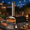 Artisan pizza being removed from an outdoor pizza oven at night