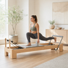 Woman performing a controlled workout on a wooden Pilates reformer